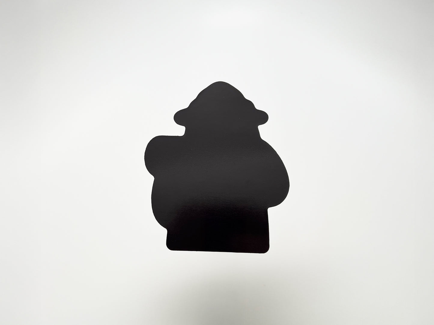 Back view of a handmade die-cut fridge magnet shaped like a cartoon bear camper. The solid black magnet silhouette highlights its custom cut design and durable finish. Perfect quirky fridge magnet gift for campers, hikers, and outdoor lovers, made to stick securely on any magnetic surface.