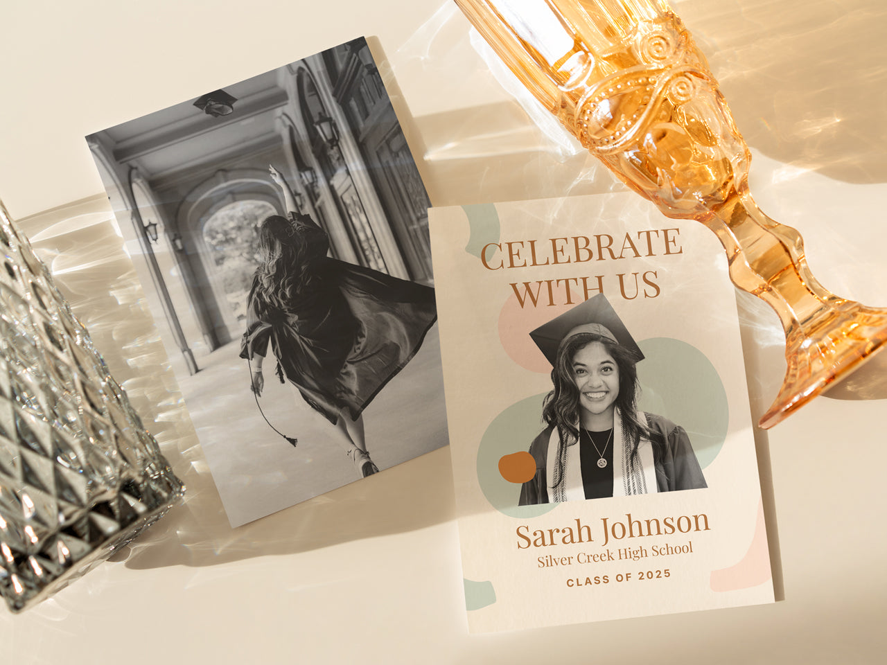 A modern boho graduation announcement card with a warm, neutral color palette, featuring abstract shapes and a custom graduate photo. The card is displayed in natural light with elegant glassware, creating a sophisticated and organic look. A personalized printed grad announcement card, available in 5x7 inches in size, ideal for high school and college graduates. Perfect for celebrating a special milestone in style.
