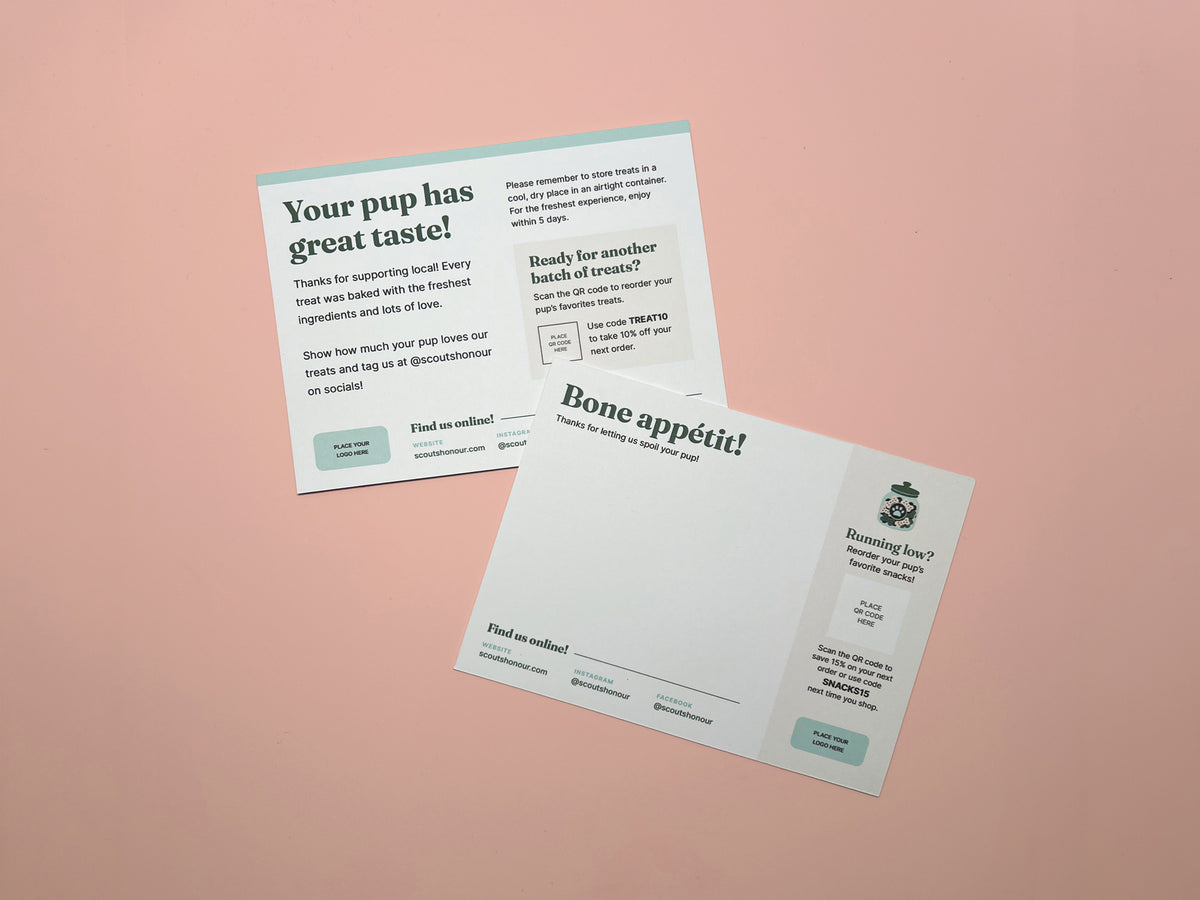 Two back layouts of printed pet treat cards or postcards laid on a soft pink background. One card reads 'Your pup has great taste!' and the other reads 'Bone appetit!'.