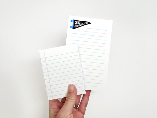 Hand holding a mini lined notepad and matching Chaos Coordinator lined notepad, showing the size difference between the 3 x 4 and 3.8 x 6 notepads.