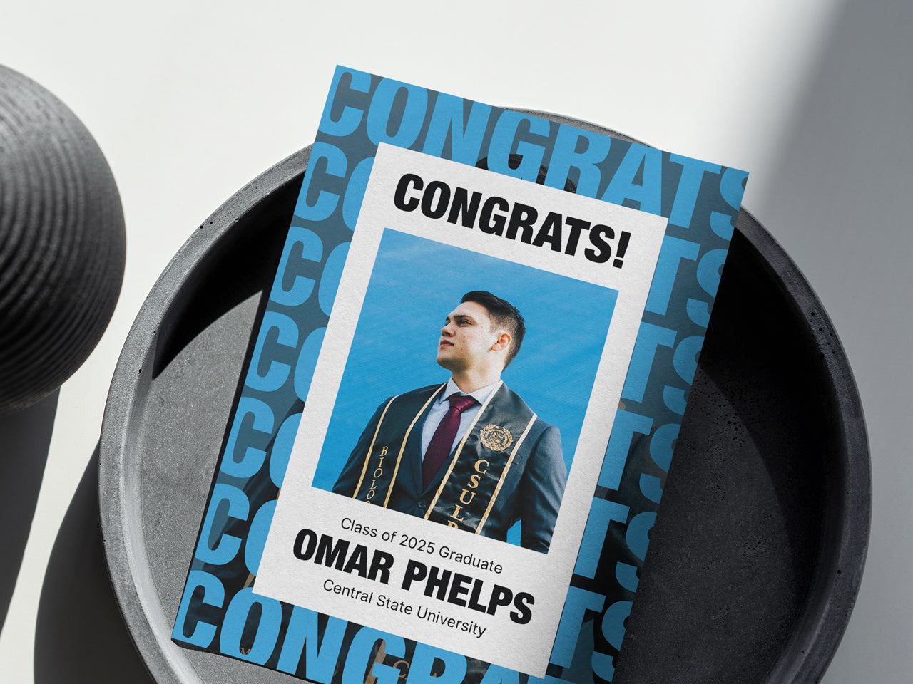 A bold graduation announcement card is placed in a sleek, minimalist black and white setting, emphasizing its modern and unisex design. The card features strong typography, a high-contrast color palette, and a structured layout that balances contemporary style with classic elegance. The graduate’s photo, name, school, and class year are displayed front and center, creating a striking personalized keepsake. A perfect choice for graduates who prefer a modern and bold design.