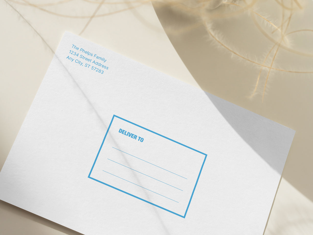 A high-quality graduation announcement envelope with custom printed return address is showcased in a soft, natural setting. The minimalist envelope design includes a printed return address in a clean, modern font and a structured Deliver To address box in blue ink, making it easy to send out announcements in style. This optional upgrade adds a polished look to any graduation announcement order. A perfect addition for college or high school graduation cards, ensuring an elegant mailing process.