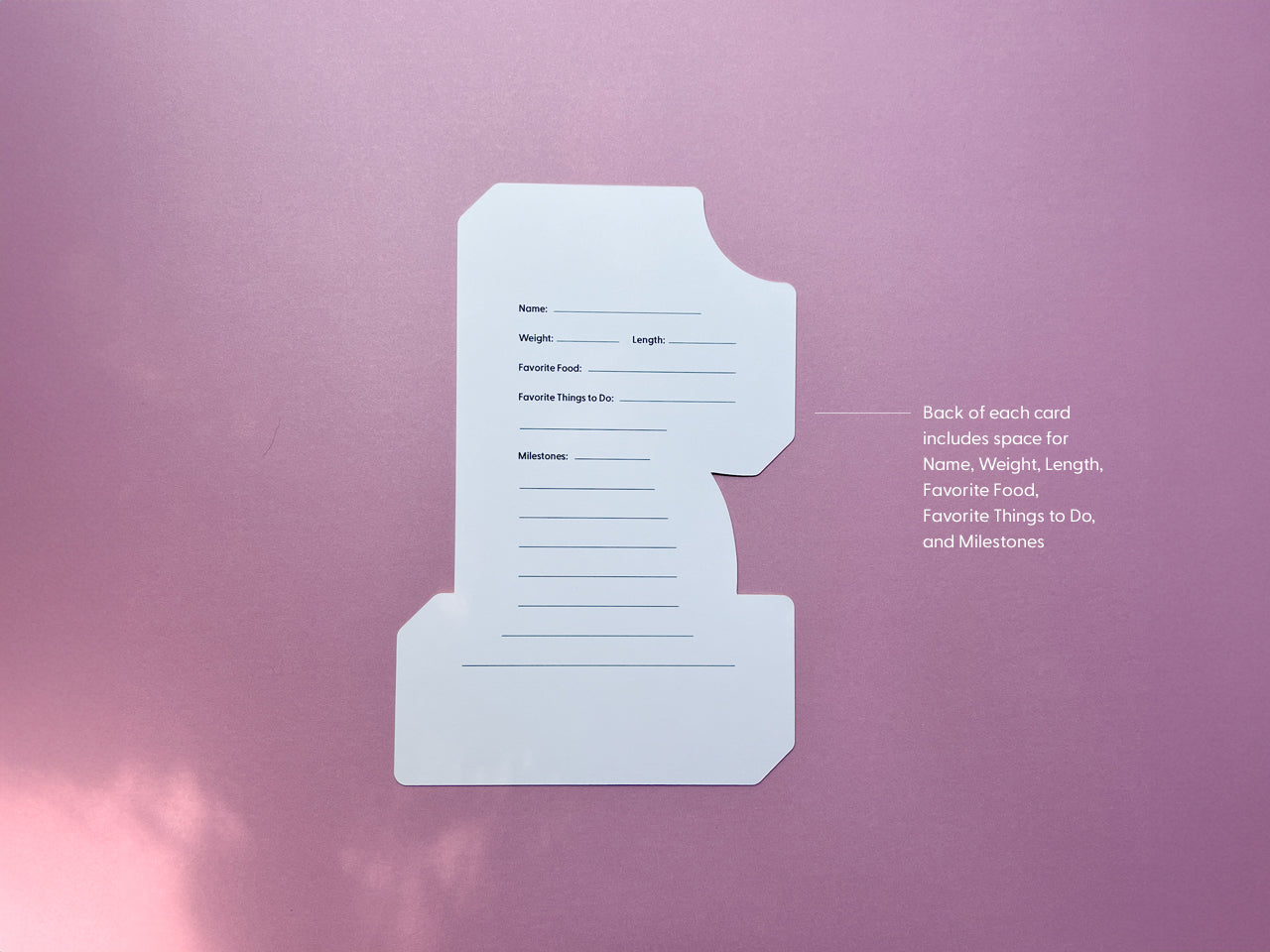 The back side of a milestone card in the shape of the number 1, featuring blank lines for documenting baby's name, weight, length, favorite food, favorite activities, and milestones. Ideal for tracking first-year growth and memories.
