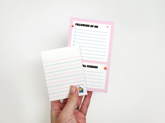 Hand holding a lined memo notepad in front of a matching "Following Up On" office checklist pad, ideal for coworker gifts and desk organization.