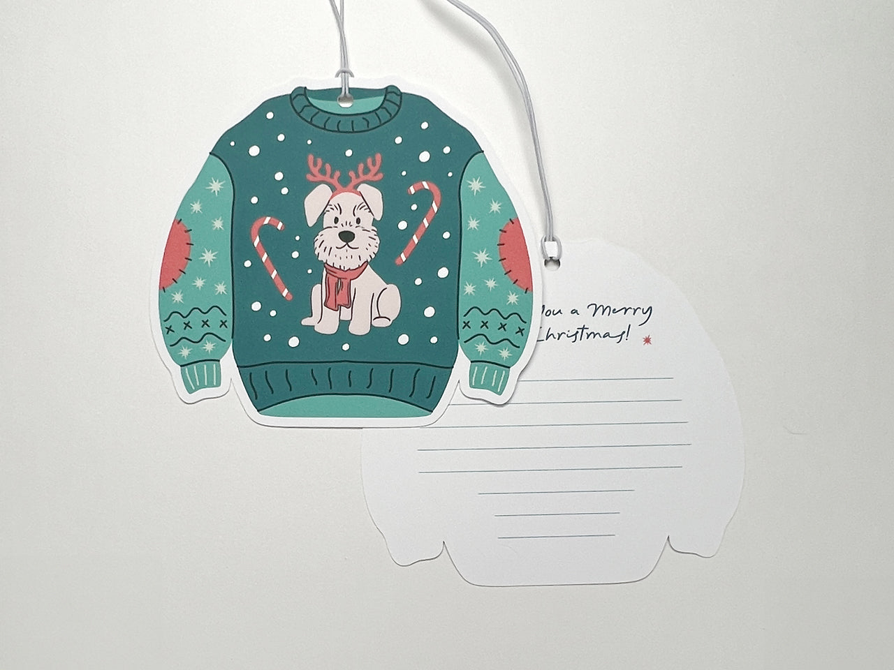 The front and back of a Christmas sweater gift tag, showcasing both a fun dog illustration on the sweater and the space for a personalized message on the back. A white string is attached for easy use.