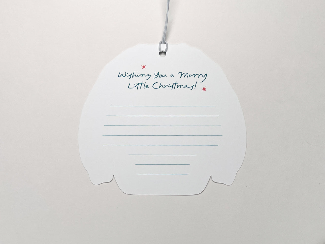 The back of a Christmas sweater gift tag with a space for a handwritten note. The message at the top reads, "Wishing You a Merry Little Christmas!" with lines below for neat writing. The background is a clean white, highlighting the design.