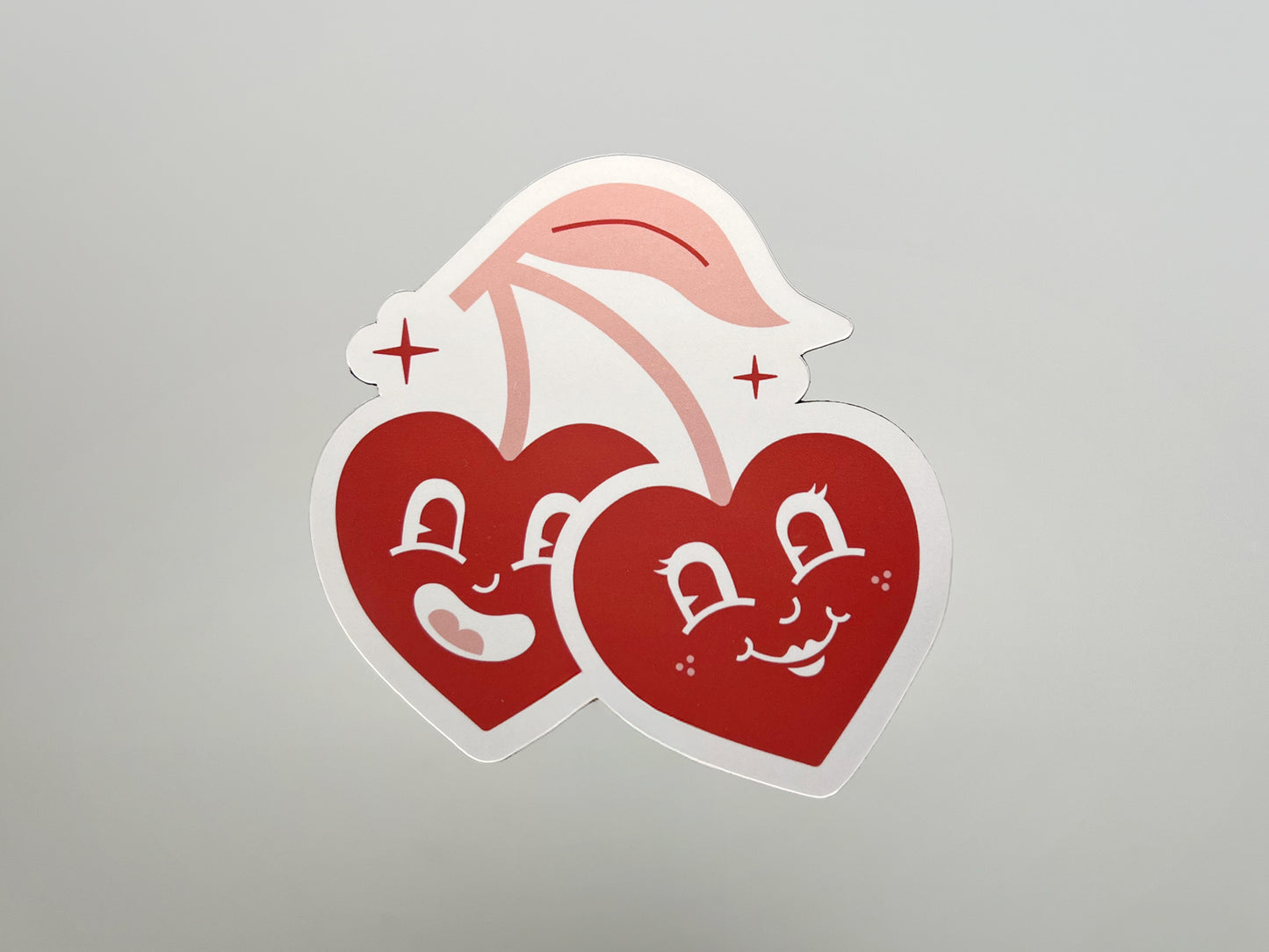 Handmade die-cut magnet featuring two smiling retro cherry hearts with cartoon faces and pink stems, set against a plain background. This fun and customizable wedding favor magnet makes a playful keepsake for couples and guests to cherish.