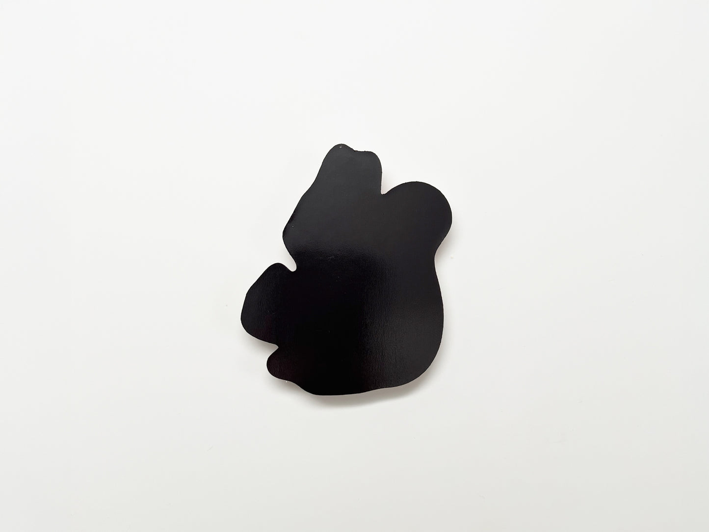 Back view of a handmade die-cut fridge magnet shaped like a squirrel, showing the smooth black magnetic surface designed to securely attach to refrigerators, lockers, or other magnetic surfaces.