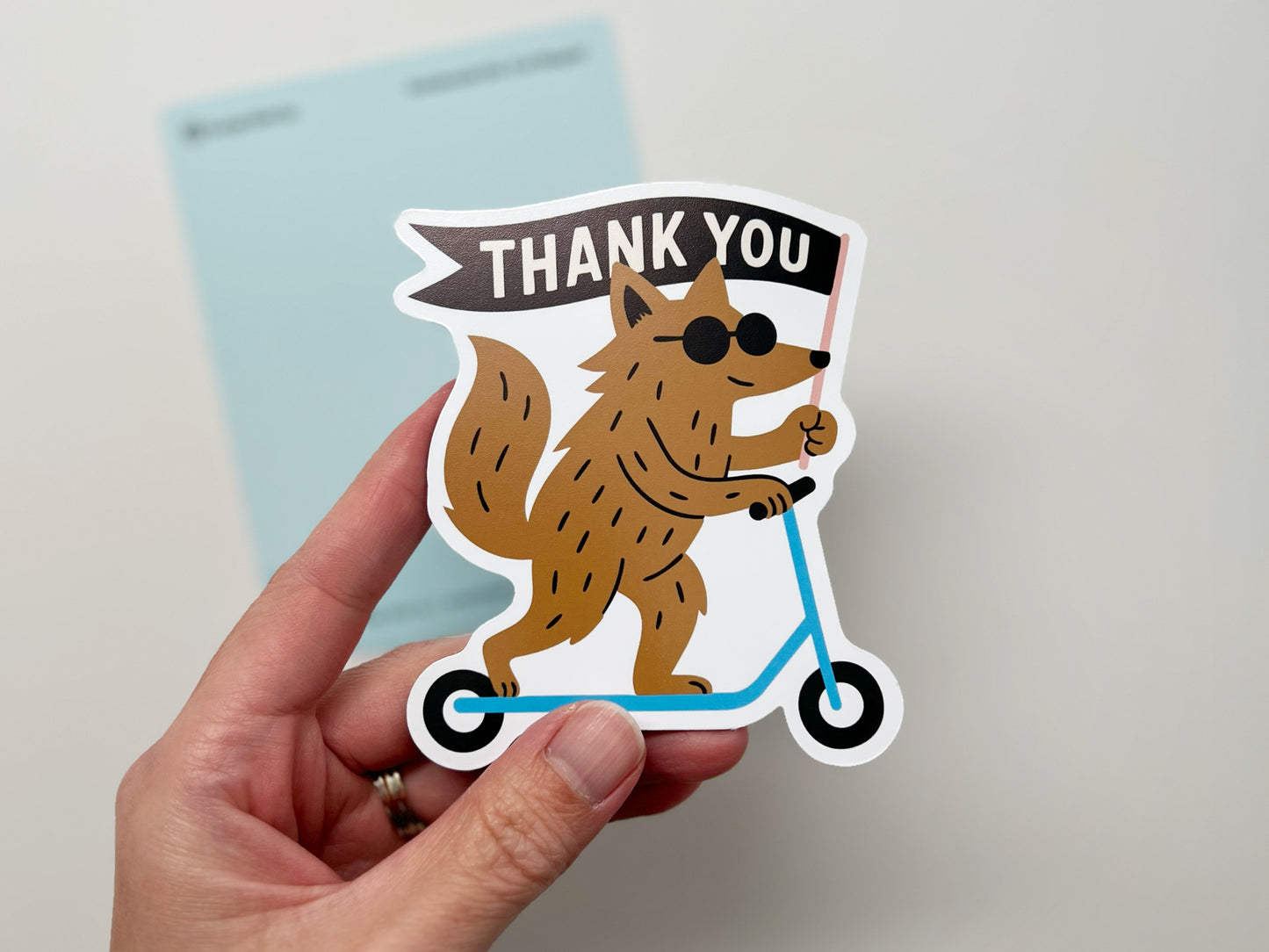 Handmade die-cut magnet featuring a quirky woodland creature on a blue scooter holding a “THANK YOU” flag. Fun, unique fridge magnet gift for animal lovers, friends, or coworkers. Cute thank you magnet perfect for quirky home décor.