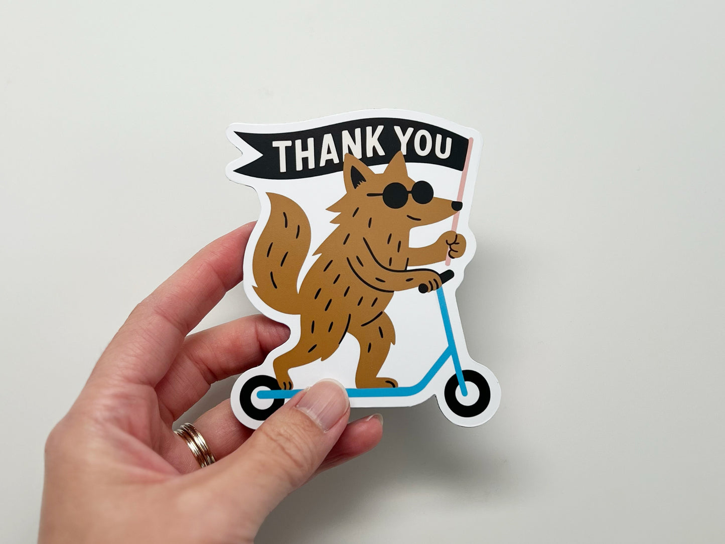 Handmade die-cut magnet featuring a quirky woodland creature on a blue scooter holding a “THANK YOU” flag. Fun, unique fridge magnet gift for animal lovers, friends, or coworkers. Cute thank you magnet perfect for quirky home décor.