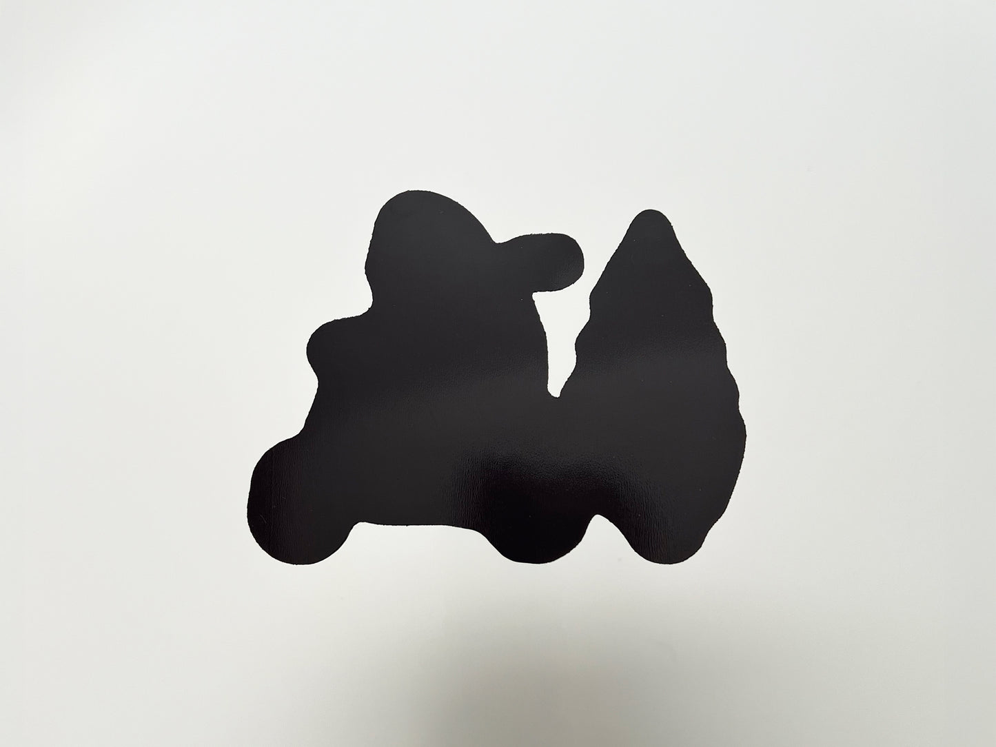 Back view of a handmade die-cut magnet shaped like a yeti riding a scooter and pulling a Christmas tree. The magnet side is solid black with a glossy finish, cut precisely to match the front design, showing durability and strong hold for use on fridges, lockers, or other magnetic surfaces.