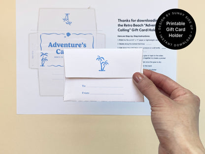 Hand holding the back of a folded printable gift card holder with a retro beach theme. The envelope features a small blue palm tree illustration and "To/From" lines for personalization. Printed instructions and the full design template are visible in the background on off-white paper. Set against a soft beige surface, this DIY gift card holder is ideal for graduations, travel gifts, or farewell occasions. A charming and customizable instant download for creative and meaningful gifting.
