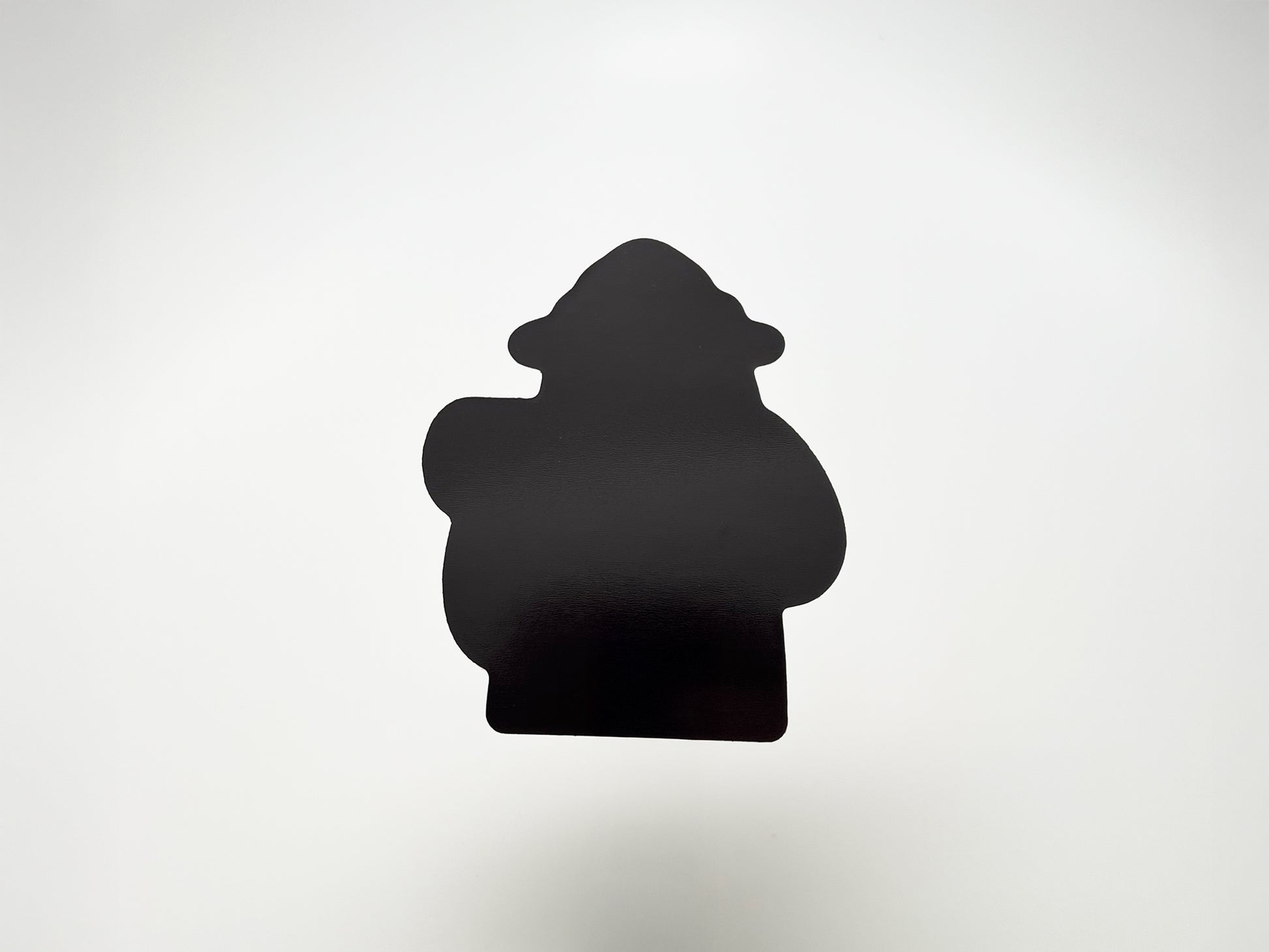 Back view of a handmade die-cut fridge magnet shaped like a cartoon bear camper. The solid black magnet silhouette highlights its custom cut design and durable finish. Perfect quirky fridge magnet gift for campers, hikers, and outdoor lovers, made to stick securely on any magnetic surface.