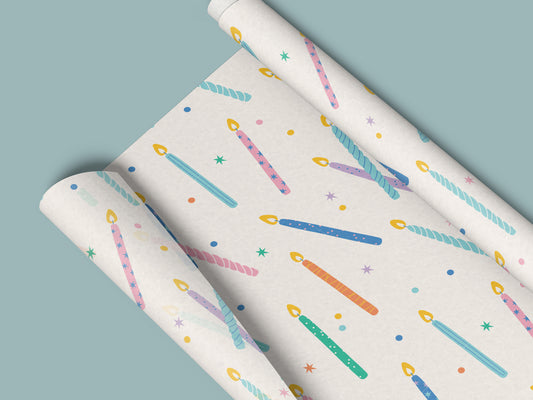 Birthday candles seamless pattern with colorful candles, stars, and confetti on cream, shown on a rolled wrapping paper mockup.