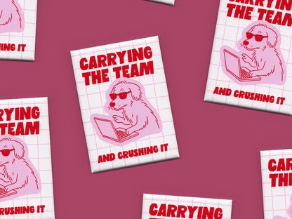 Multiple rectangular magnets scattered across a dark pink background featuring bold red text that says “Carrying the Team and Crushing It” with a pink illustration of a dog wearing sunglasses while working on a laptop over a light pink grid design.