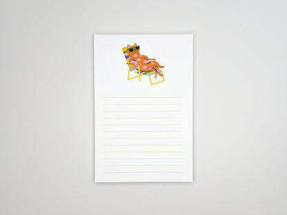 Flat lay of a 4x6 lined notepad centered on a white background, featuring a colorful illustration at the top of a pink polka-dot cat wearing green sunglasses while relaxing on a rainbow-striped lounge chair. Light yellow writing lines fill the lower half of the page. The minimalist memo pad has a playful summer vibe and is designed as a cute desk notepad for cat lovers, perfect for notes, reminders, or gifting.