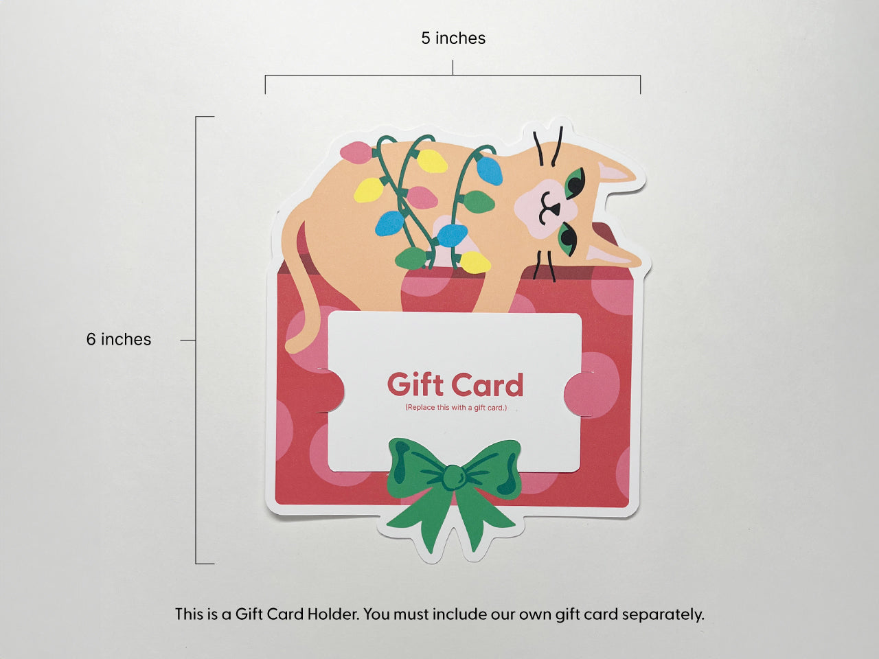 A front view of a Christmas cat gift card holder with measurements displayed (5 x 6 inches). The vibrant design includes an orange cat wrapped in colorful lights on a red and pink gift box, complete with slots for holding a gift card.