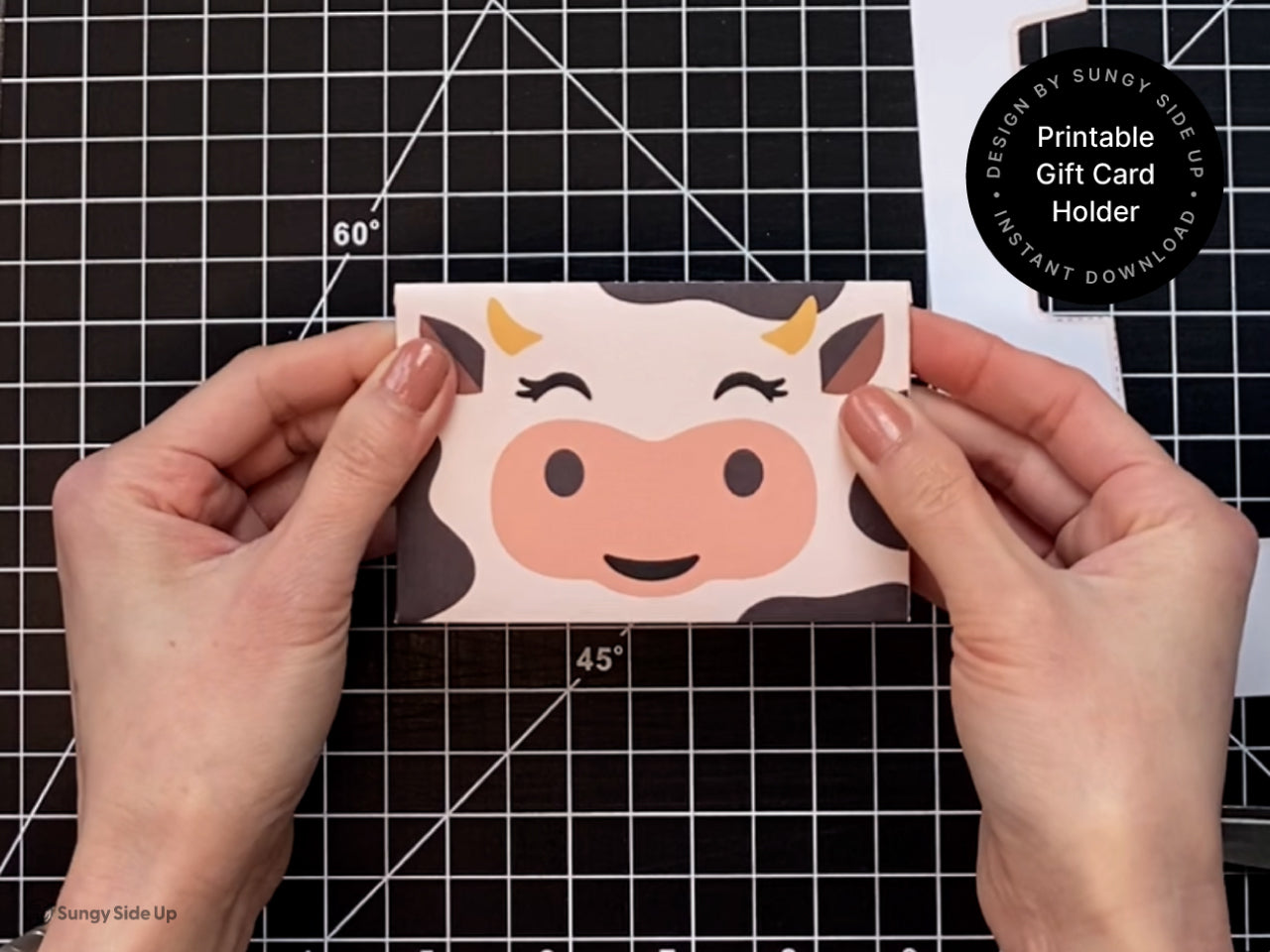 Hands holding a finished printable cow gift card holder with a cute cow face design on the front. This DIY gift card envelope is ideal for birthdays, teacher appreciation, or baby shower favors. Printed and assembled at home, the cardholder adds a fun farm animal theme to your gift presentation. This instant download template is perfect for anyone who loves crafting unique and memorable gift card packaging.