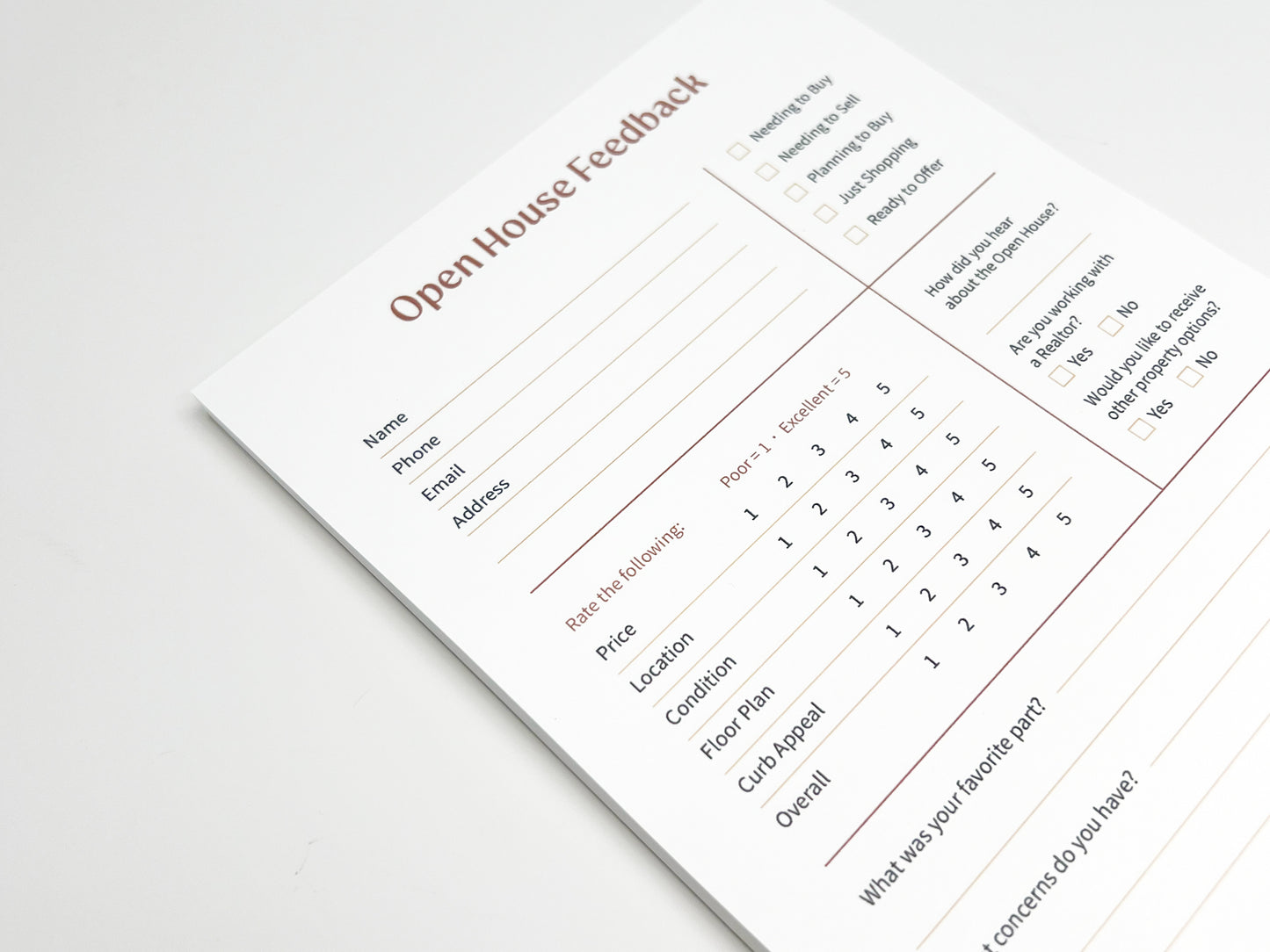 Angled close-up of a custom 5 × 8 Open House Feedback real estate notepad showing structured sections for buyer contact details, purchase readiness checkboxes, property rating scales for price, location, condition, floor plan and curb appeal, plus open-ended feedback fields designed for real estate open house follow-up.
