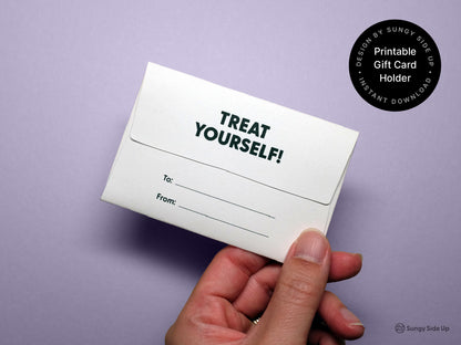 Hand holding the back of the completed printable dog gift card holder on a purple background. The back flap shows the phrase Treat Yourself in bold uppercase letters, with labeled lines for To and From. A round black label in the top right highlights Printable Gift Card Holder and Instant Download with the Sungy Side Up brand. The photo emphasizes the back design and customization features.