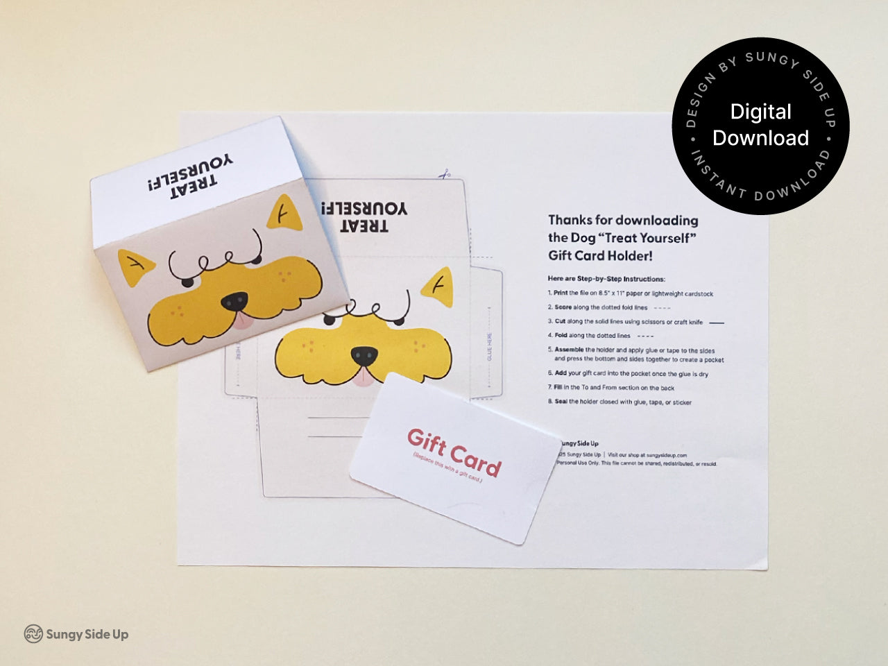 Flat lay image showing the printed template for the dog Treat Yourself gift card holder on a white sheet with step-by-step instructions. Two finished card holders are displayed with one flipped to show the back. A blank gift card labeled Gift Card lies on top. A round label in the top right corner reads Digital Download and Designed by Sungy Side Up. The image highlights both the assembly sheet and final product.