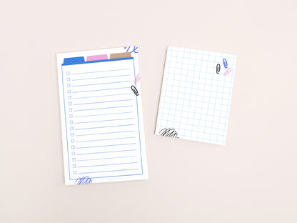 A lined checklist notepad and a small grid notepad with colorful office-themed illustrations displayed side by side on a light background.
