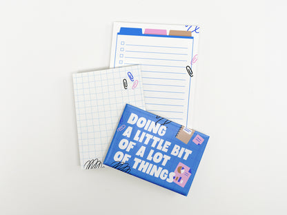 A blue magnet reading "Doing a Little Bit of a Lot of Things" displayed alongside a mini grid notepad and a lined checklist notepad on a white background.