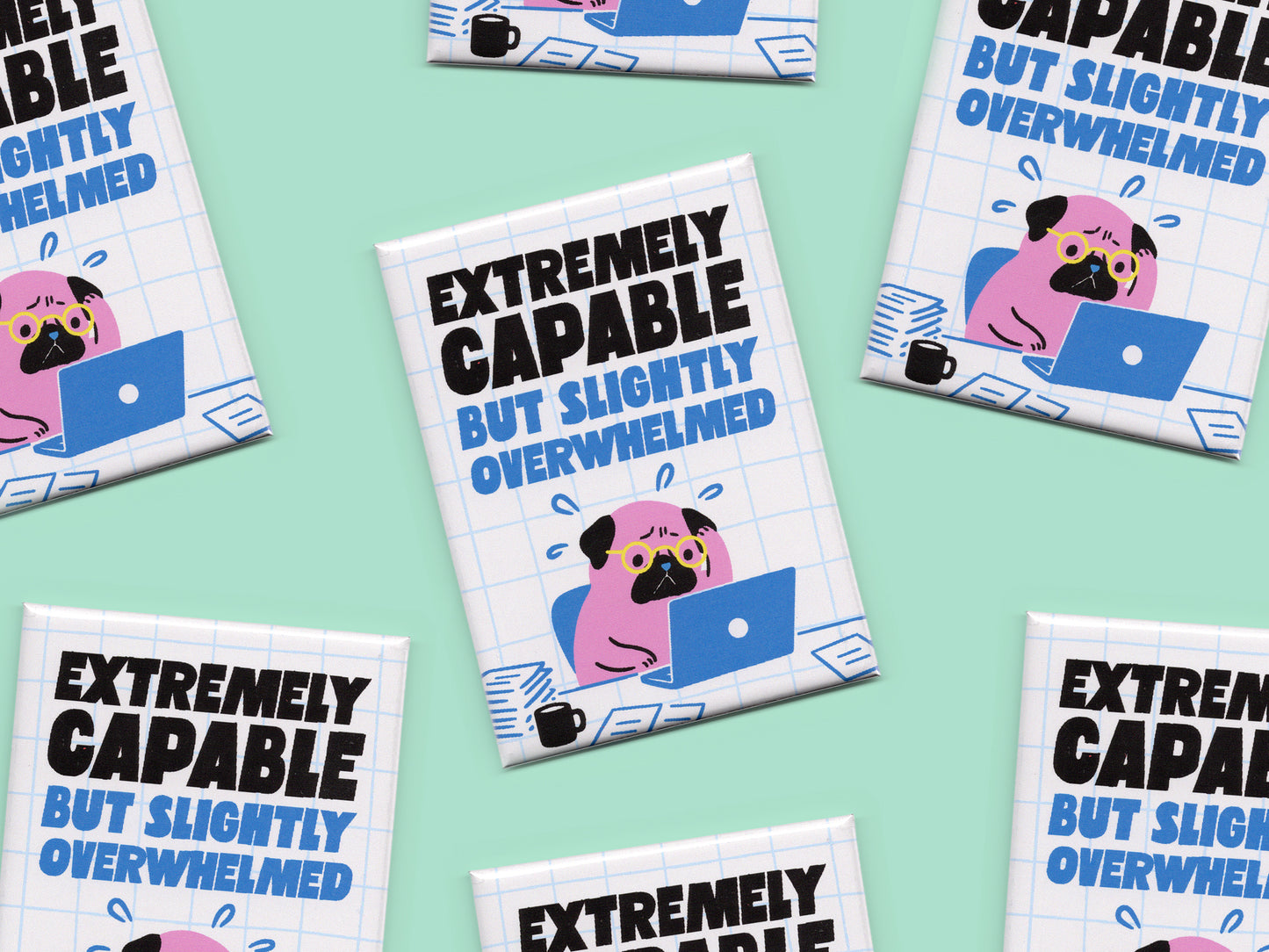 Multiple rectangular magnets displayed on a mint green background with bold black and blue text reading “Extremely Capable But Slightly Overwhelmed.” Each magnet features a stressed pink pug wearing glasses while working on a blue laptop surrounded by papers and a coffee mug on a white grid background.