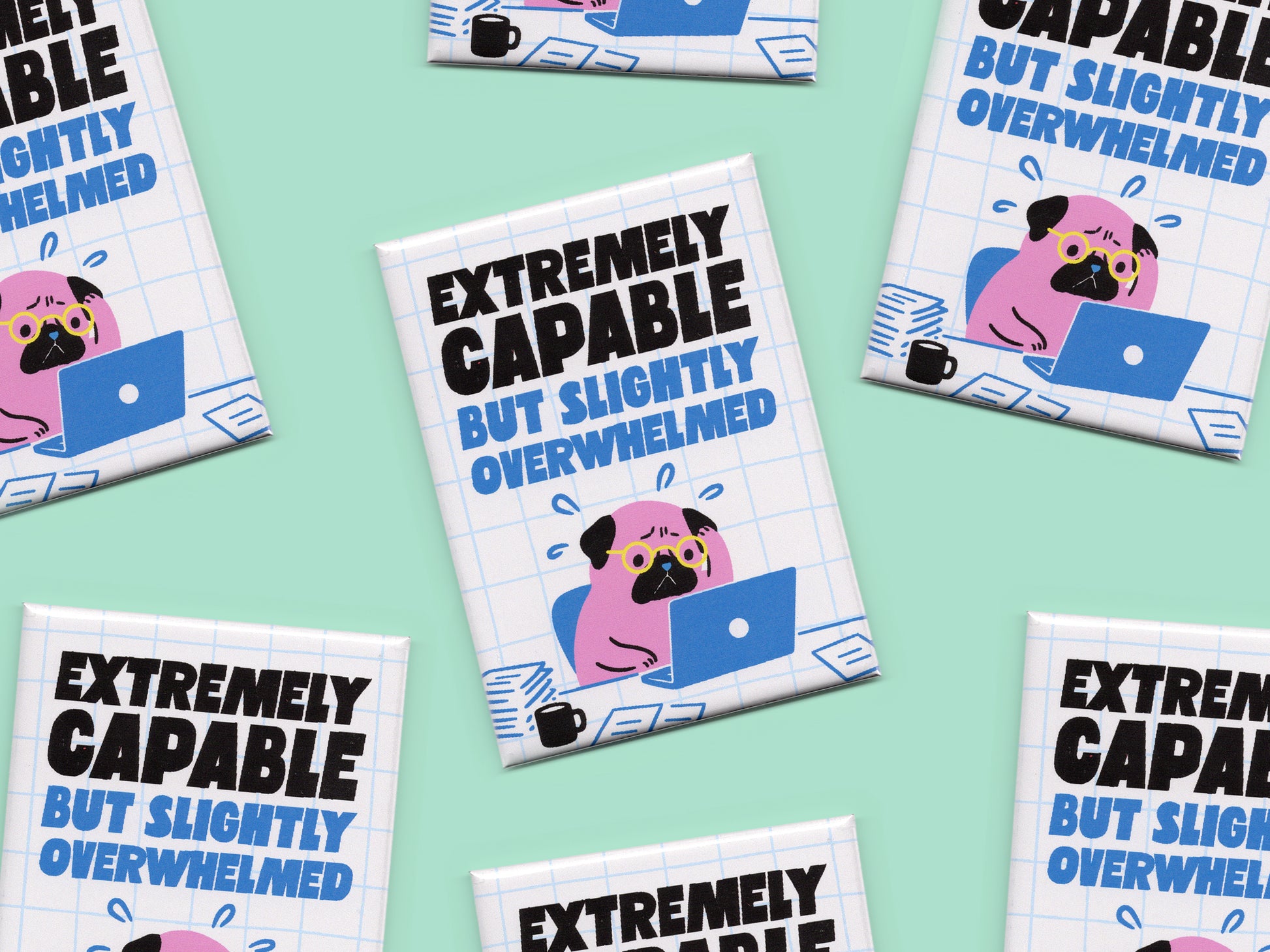 Multiple rectangular magnets displayed on a mint green background with bold black and blue text reading “Extremely Capable But Slightly Overwhelmed.” Each magnet features a stressed pink pug wearing glasses while working on a blue laptop surrounded by papers and a coffee mug on a white grid background.