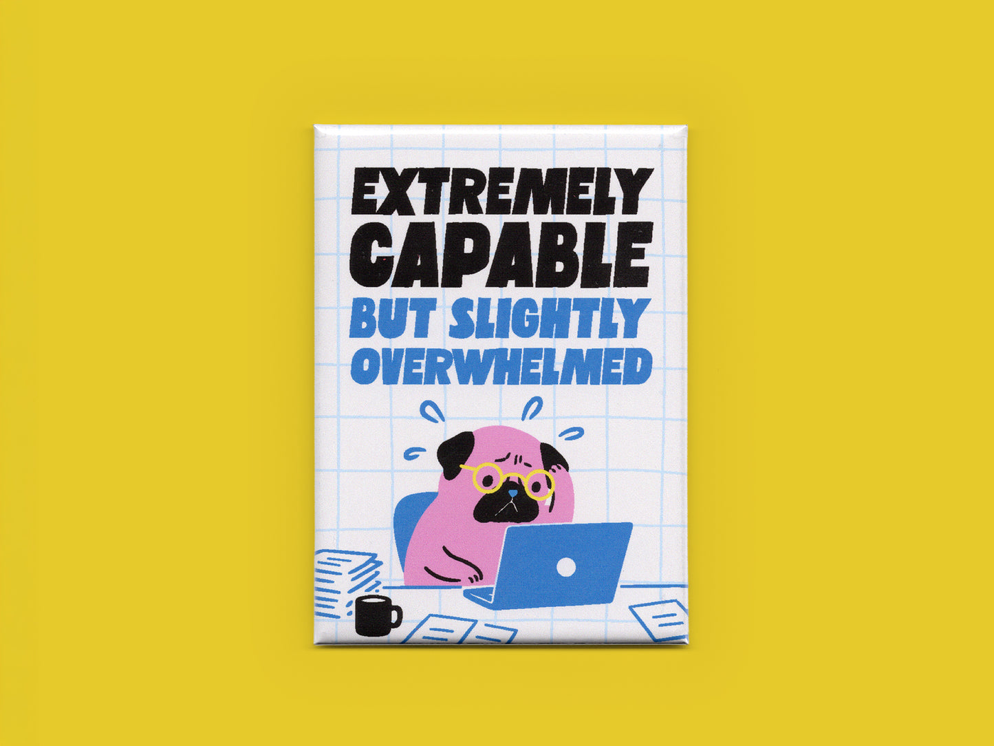 Rectangular magnet on a yellow background with bold black and blue text reading “Extremely Capable But Slightly Overwhelmed.” The design features a stressed pink pug wearing glasses while working on a blue laptop surrounded by papers and a coffee mug on a white grid background.