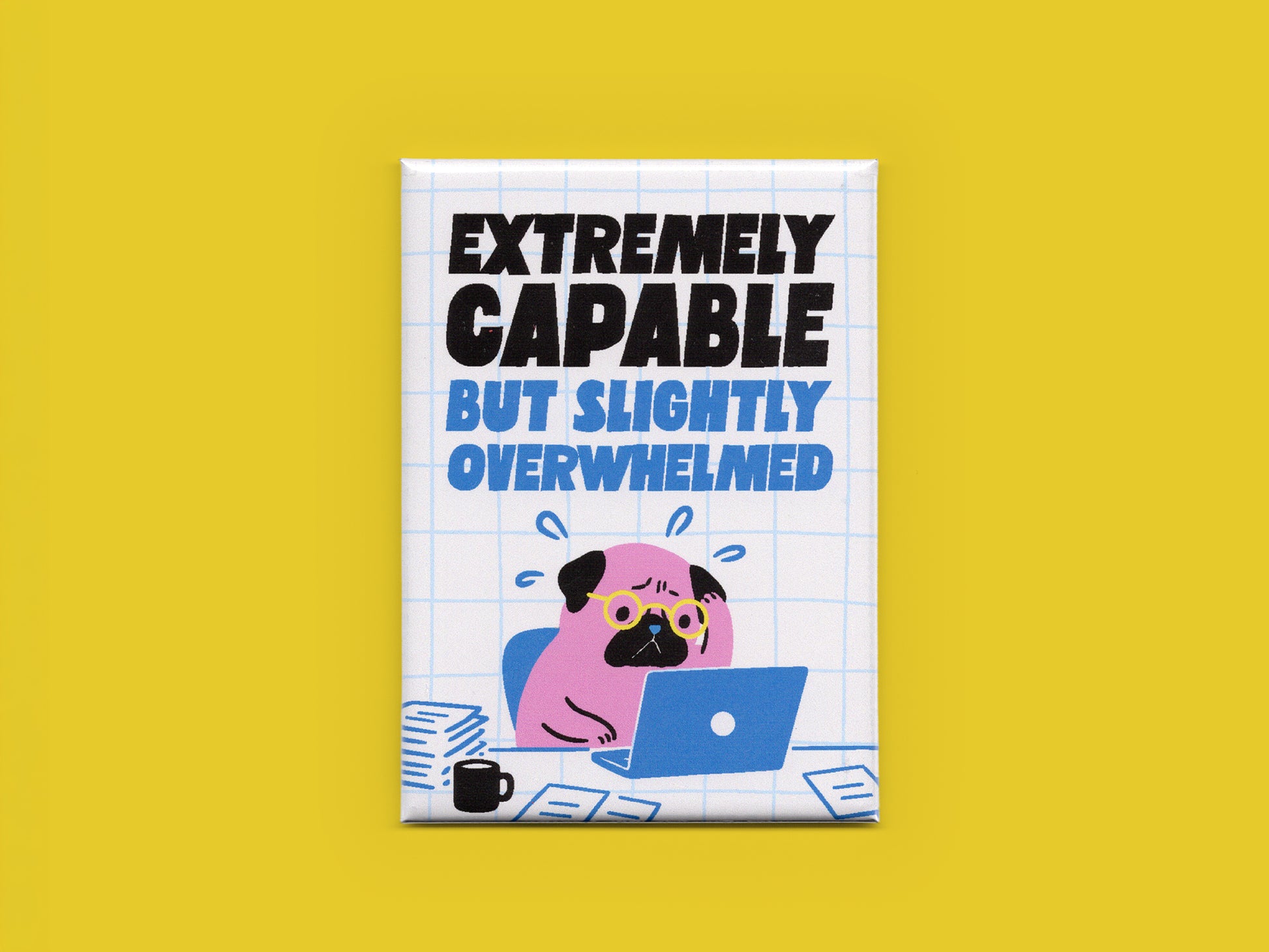 Rectangular magnet on a yellow background with bold black and blue text reading “Extremely Capable But Slightly Overwhelmed.” The design features a stressed pink pug wearing glasses while working on a blue laptop surrounded by papers and a coffee mug on a white grid background.