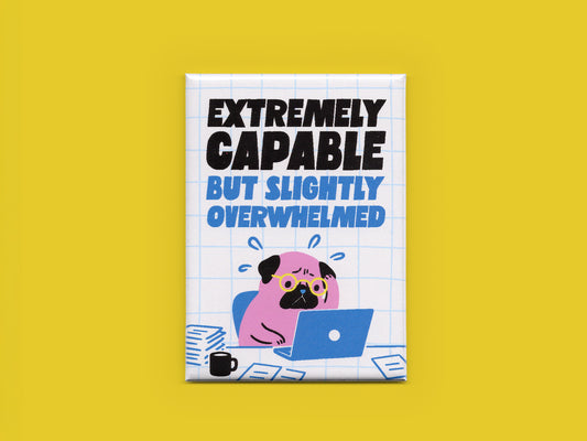 Rectangular magnet on a yellow background with bold black and blue text reading “Extremely Capable But Slightly Overwhelmed.” The design features a stressed pink pug wearing glasses while working on a blue laptop surrounded by papers and a coffee mug on a white grid background.