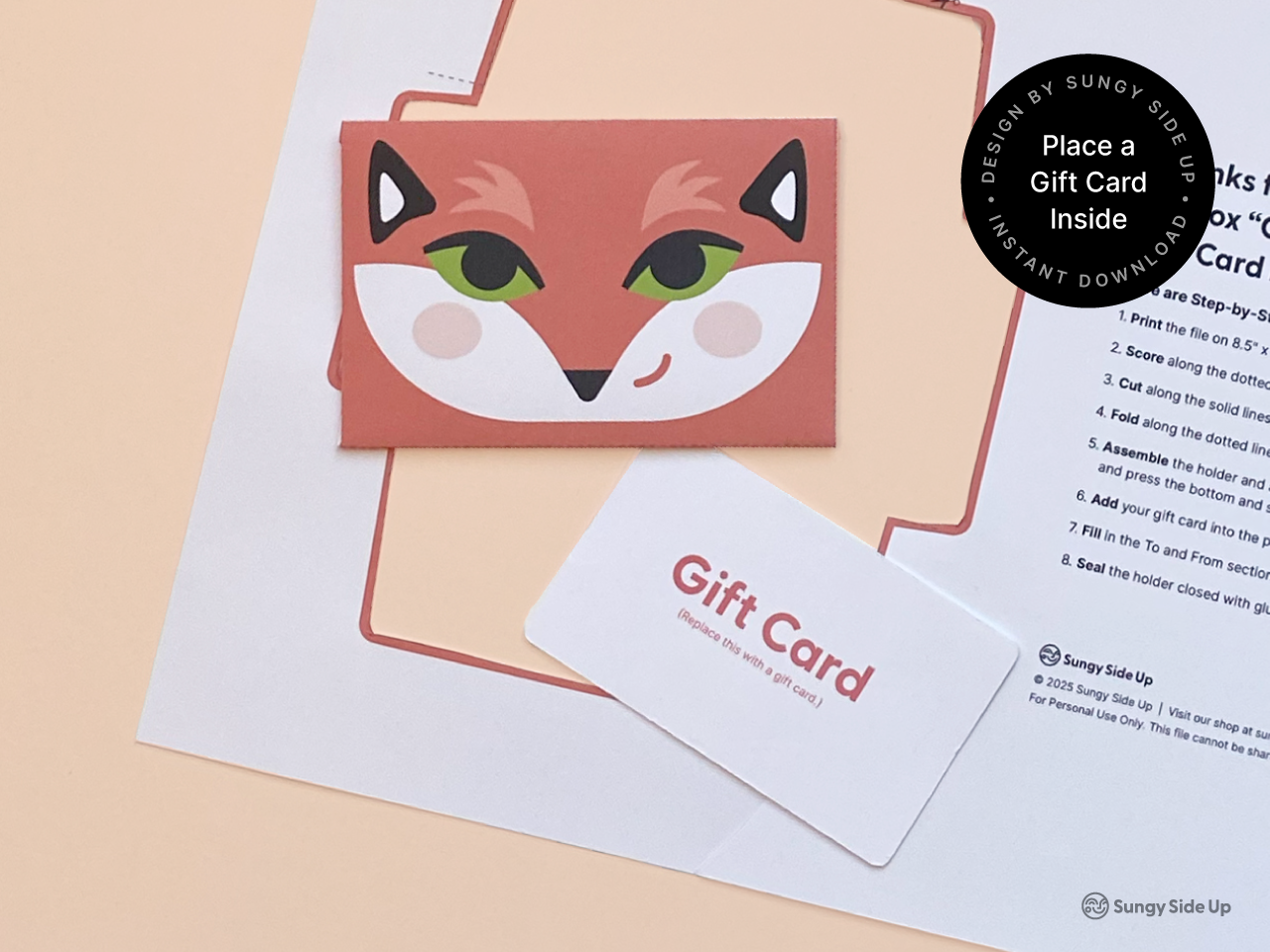 Printable fox gift card holder template displayed with a mock gift card on a peach background. The finished envelope features a cheerful fox face and is perfect for holding standard-sized gift cards. This DIY digital download comes with clear instructions and is ideal for birthdays, teacher gifts, or thoughtful surprises. Designed for easy at-home assembly with 8.5" x 11" paper.