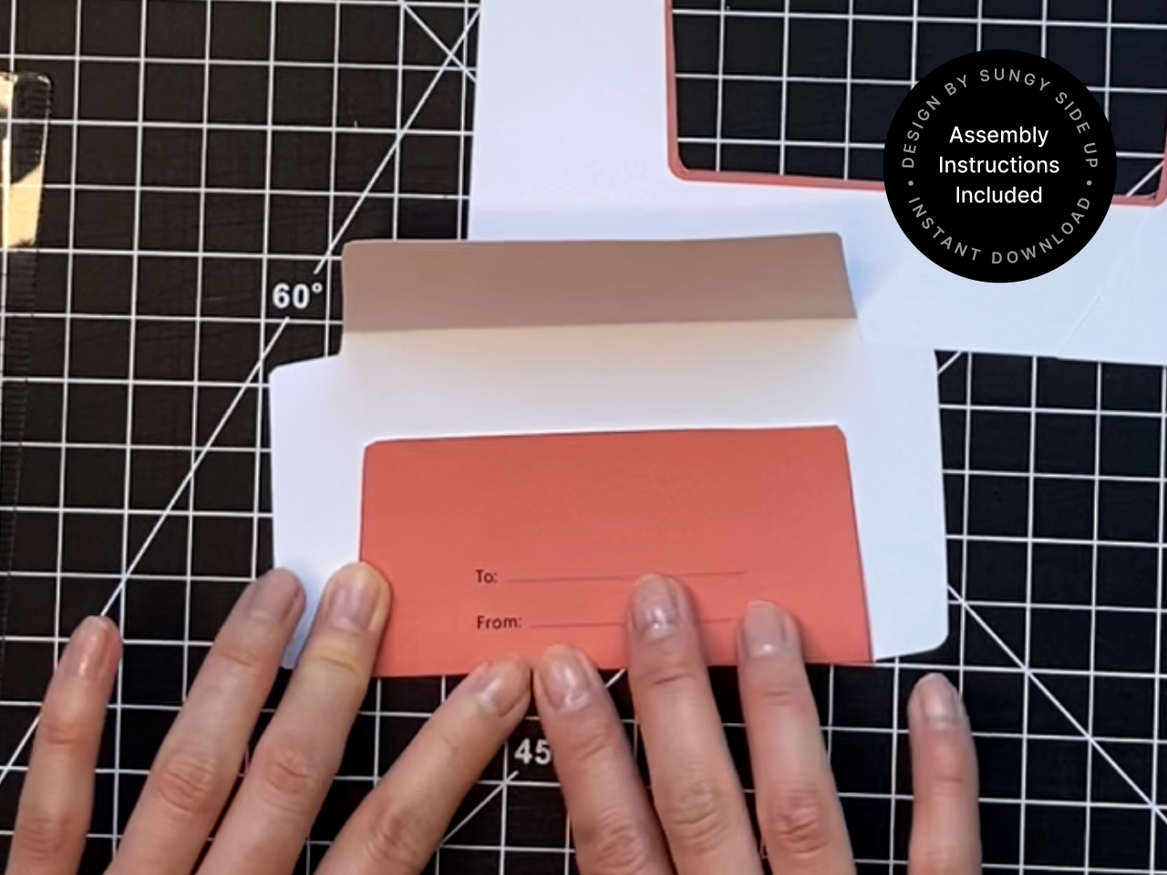 Hands assembling a printable fox gift card holder template on a black cutting mat. The back flap is folded open to reveal the To and From section, ideal for personalizing each envelope. This DIY gift card envelope is a digital download designed for easy crafting at home. Great for birthdays, holidays, teacher gifts, and printable stationery projects.