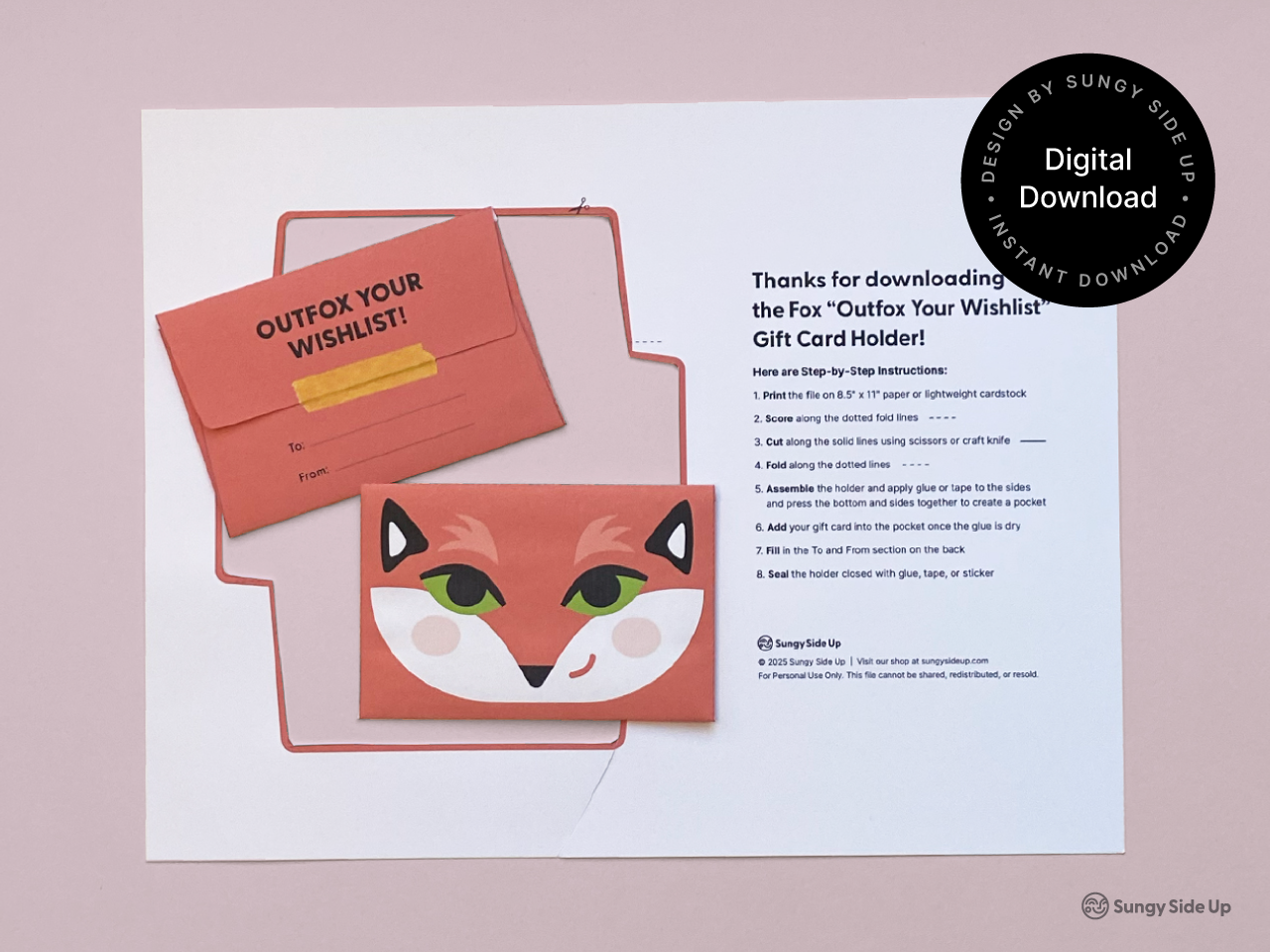 Printable fox gift card holder displayed on a soft pink background, featuring both front and back designs. The envelope includes a cheerful fox face on the front and “Outfox Your Wishlist” on the back with a To/From section. Includes a printed instruction sheet with step-by-step assembly directions. Ideal for birthdays, thank you gifts, and DIY printable craft lovers.