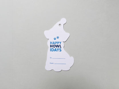 Back view of a handmade die-cut Schnauzer gift tag shaped like a dog wearing a winter hat. The tag features the phrase Happy Howlidays in playful blue text with paw print accents and lines for To and From personalization.