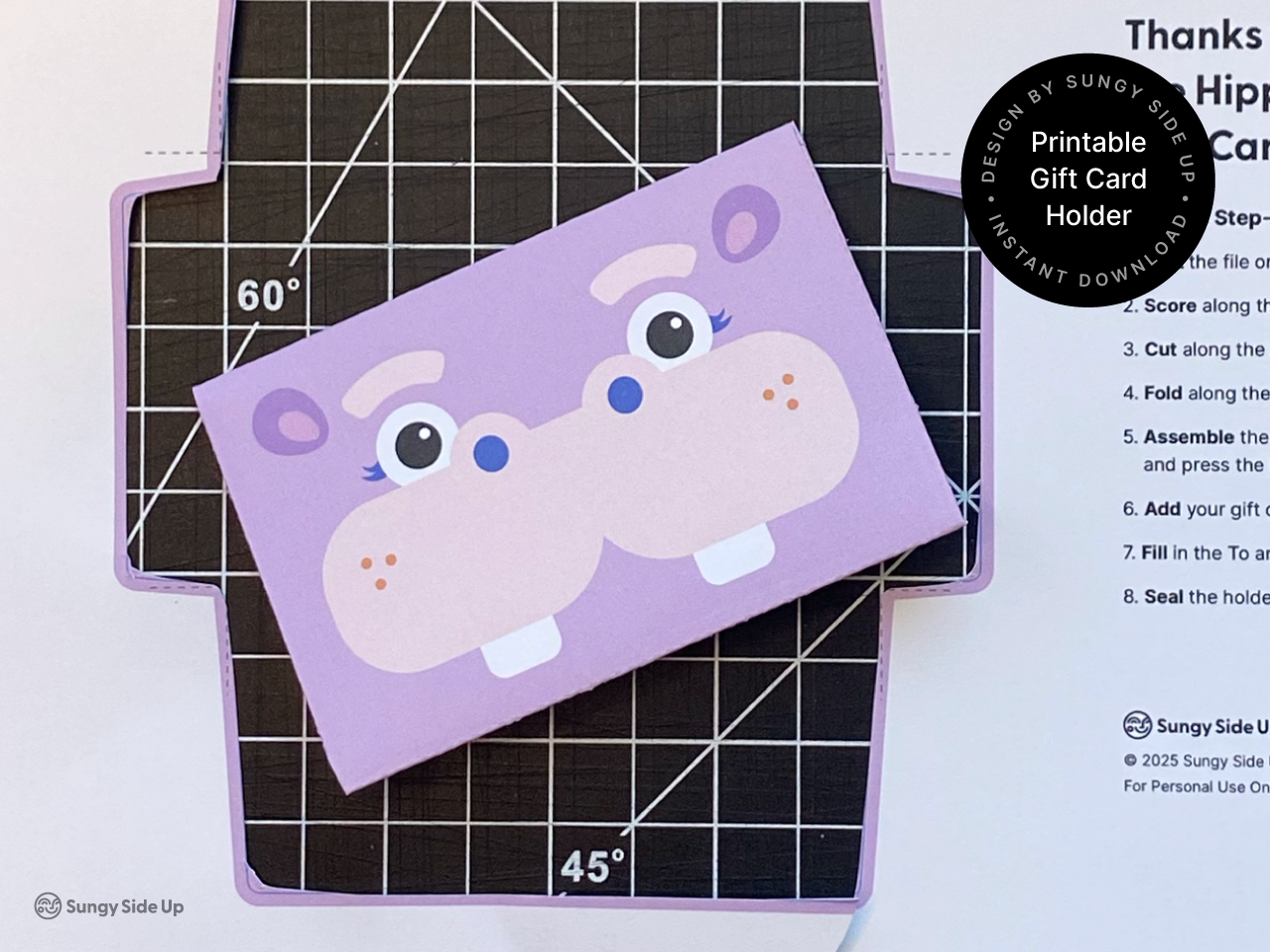 Close-up of a completed hippo gift card envelope on a cutting mat. This printable product is an instant download you can assemble at home for birthdays, kids parties, or last-minute gifts. The fun animal design makes it perfect for parents, teachers, and DIY lovers looking for creative gift wrap solutions. Easy paper craft for card gifting using cardstock and scissors.