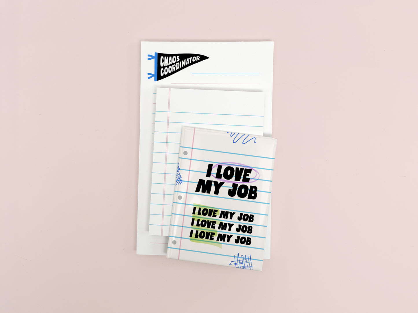 Funny coworker gift bundle featuring an I Love My Job magnet, mini lined notepad, and Chaos Coordinator notepad arranged on a soft pink background.