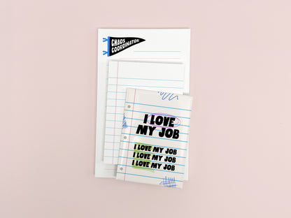 Funny coworker gift bundle featuring an I Love My Job magnet, mini lined notepad, and Chaos Coordinator notepad arranged on a soft pink background.