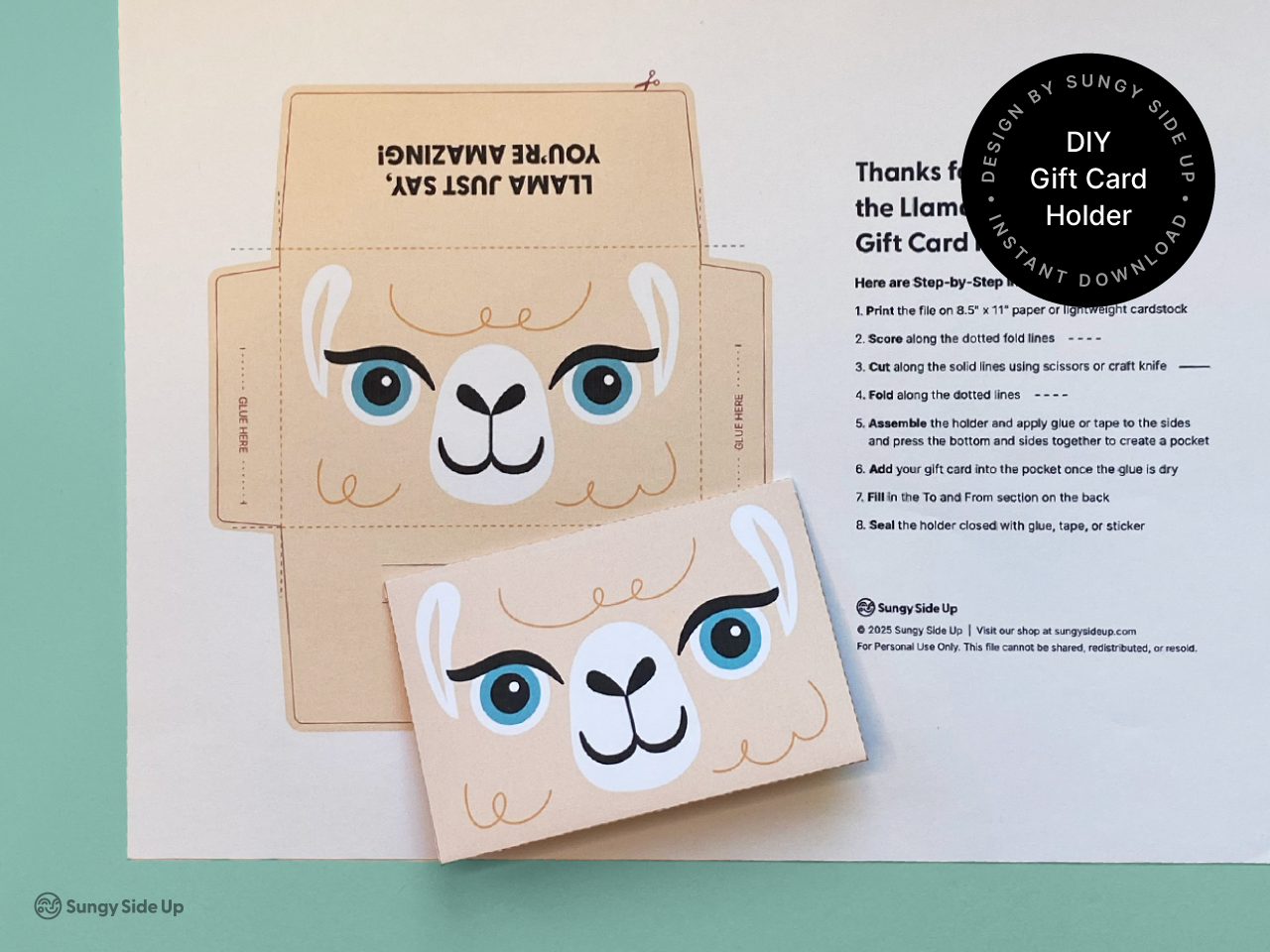 Flat lay of a llama gift card holder printable with one cut-out and fully assembled version placed on top. Set on a teal background, this image showcases the before and after of the DIY craft. Ideal for Etsy or Shopify shoppers looking for printable gift card holders for birthdays, party favors, classroom gifts, or thank you cards. This fun animal-themed digital file is easy to make and adds a personalized touch to any occasion.