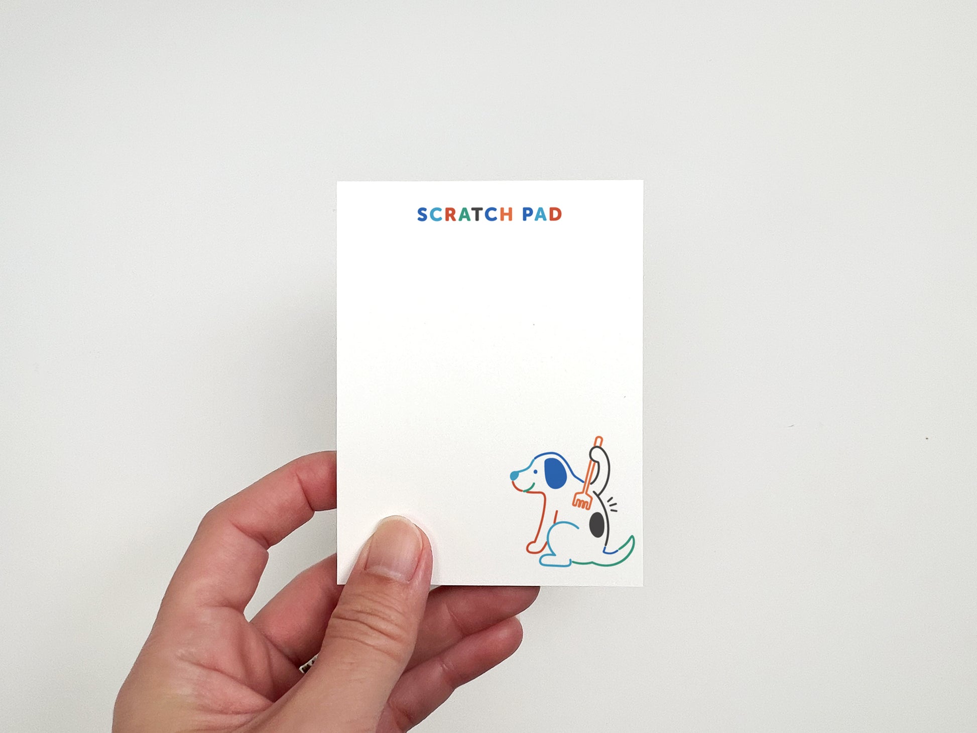 Hand holding a dog-themed scratch pad featuring a cute illustration and blank writing space for notes, reminders, and lists.