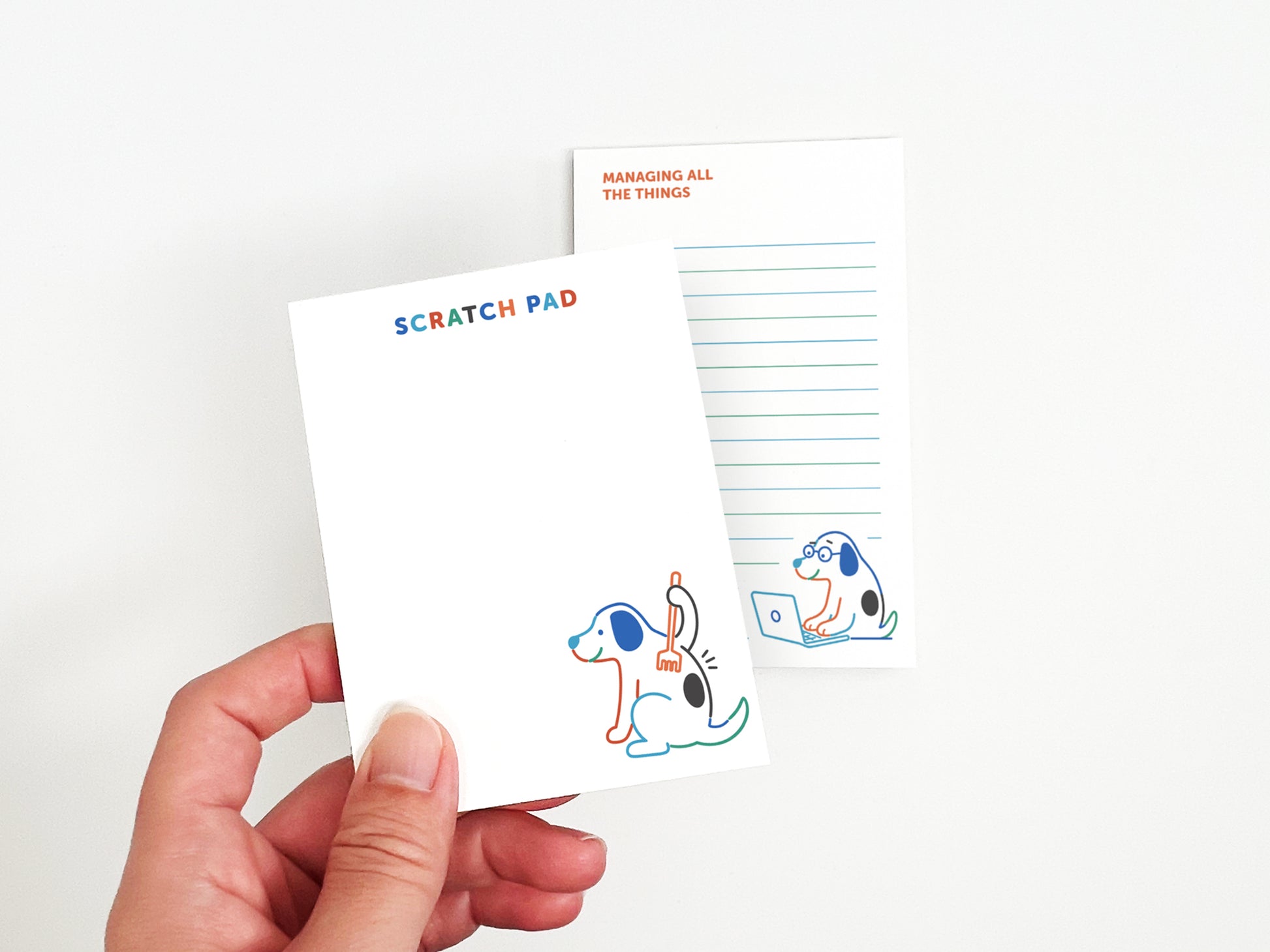 Hand holding a dog-themed scratch pad with a matching "Managing All the Things" notepad in the background, perfect for notes, reminders, lists, and desk organization.