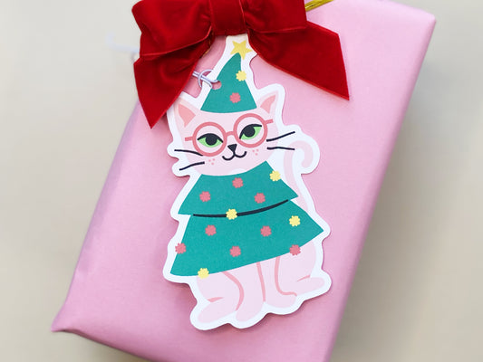 Holiday gift wrapping made fun with unique cat-themed gift tags, featuring a pink cat in a Christmas tree costume. Paired with 'Merry Christmas!' tags for adding a personal and festive touch to Christmas presents.
