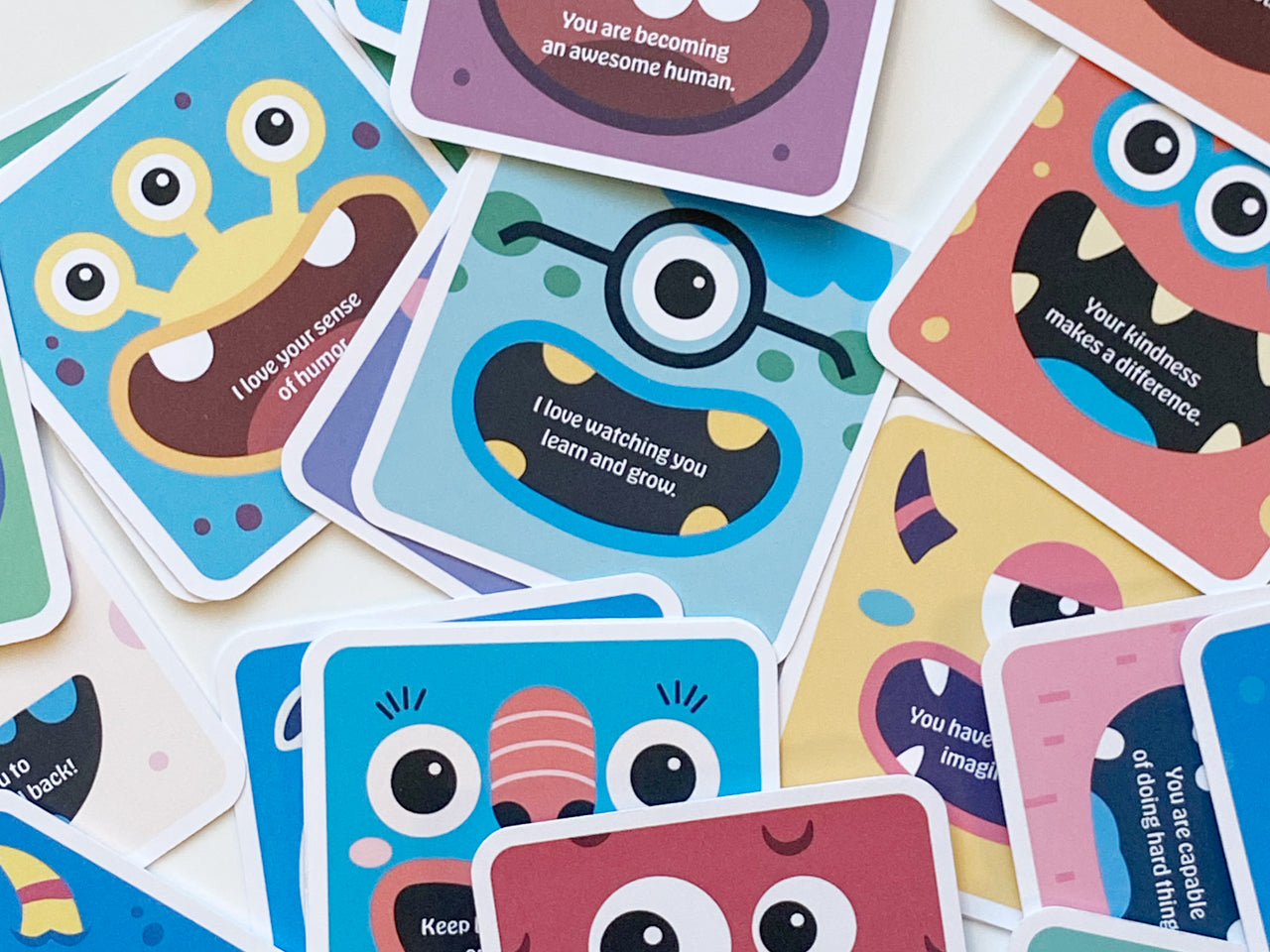 A flat lay of multiple monster-themed lunch box note cards spread out, displaying various cartoon monsters with unique designs, bright colors, and uplifting, motivational phrases. Perfect for kids lunches, party favors, or gifts.