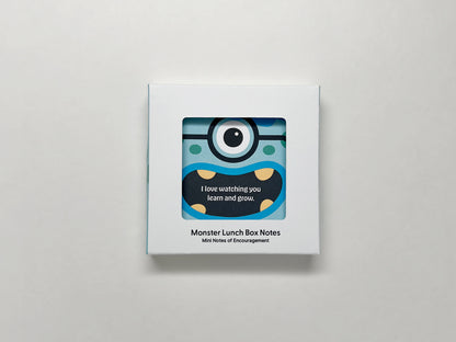 A neatly packaged box of Monster Lunch Box Notes, featuring a window showcasing a blue monster card with the message, I love watching you learn and grow. The packaging is clean and modern, with the product name displayed at the bottom.