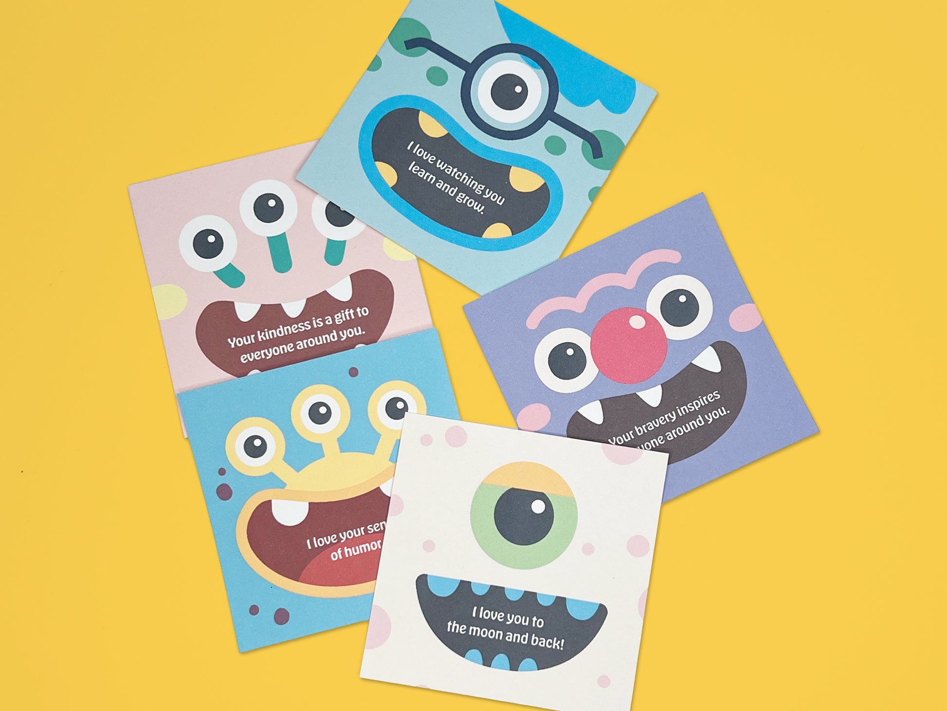 Colorful monster lunch box notes arranged on a bright yellow background, showing square 2.5-inch handmade kids lunchbox cards with playful monster faces and encouraging designs, part of a fun lunch notes notepad for school lunches and backpacks.