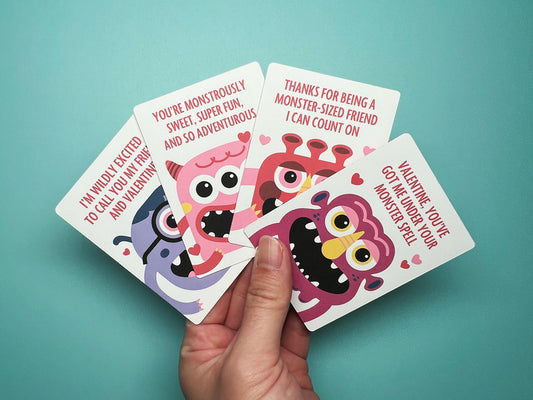 Hand holding four colorful monster-themed Valentine's Day cards against a turquoise background. Each card features a unique, cheerful monster illustration and playful Valentine messages. This creative card set is ideal for kids’ Valentine exchanges.