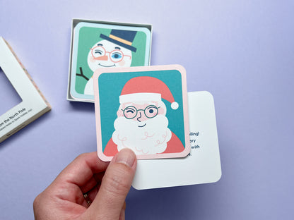 Collection of illustrated Christmas note cards with rounded corners showcasing holiday characters like Santa, a snowman, and elves. These cards are designed to bring excitement to the Christmas countdown with their charming and playful themes.