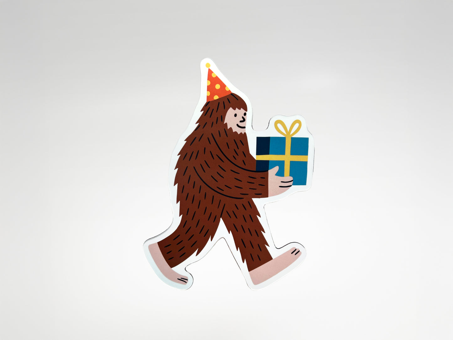 Die-cut Party Legend magnet featuring a smiling Sasquatch character wearing a red and yellow polka-dot party hat and carrying a wrapped blue gift tied with a yellow bow. This quirky Bigfoot magnet makes a unique party favor, birthday keepsake, or fun fridge decoration that adds personality to any space. Handmade and full of charm, it’s a playful gift for guests who love offbeat designs, legendary vibes, and celebrating with humor that lasts beyond the party.
