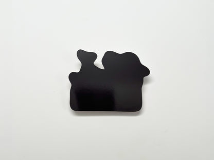 Back view of a handmade die-cut magnet, showing its solid black magnetic surface in an irregular shape. Designed to securely attach to metal surfaces like refrigerators, lockers, or filing cabinets.